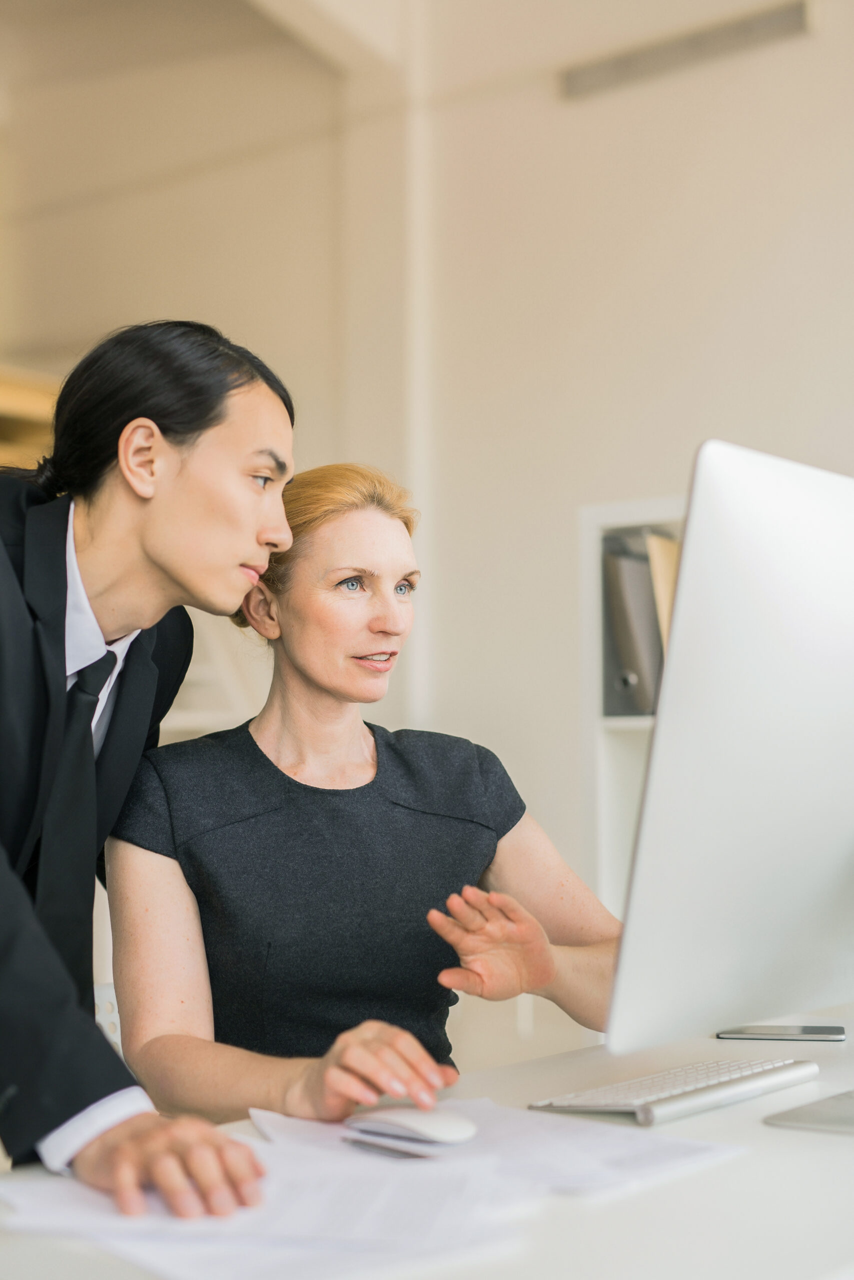 Two colleagues looking at online data in computer monitor at meeting